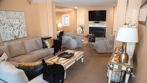 A living room with a beige sofa, a coffee table, and a fireplace. - Colorful 4-bedroom house-Vet owned-NAVAL Academy (Waukegan)