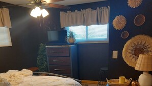A bedroom with a bed, a ceiling fan, a dresser, a lamp, and decorative wall art. - Colorful 4-bedroom house-Vet owned-NAVAL Academy (Waukegan)
