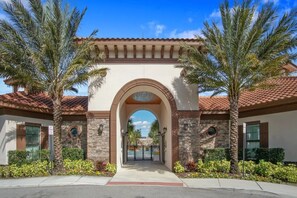 Stunning arched entrance flanked by palm trees, accessible via a gated driveway.