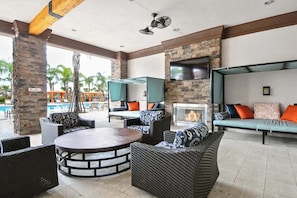 An outdoor lounge area with wicker furniture, a fire pit, and a TV screen. - Spacious 5-Bedroom Villa with Private Pool in Davenport (Davenport)