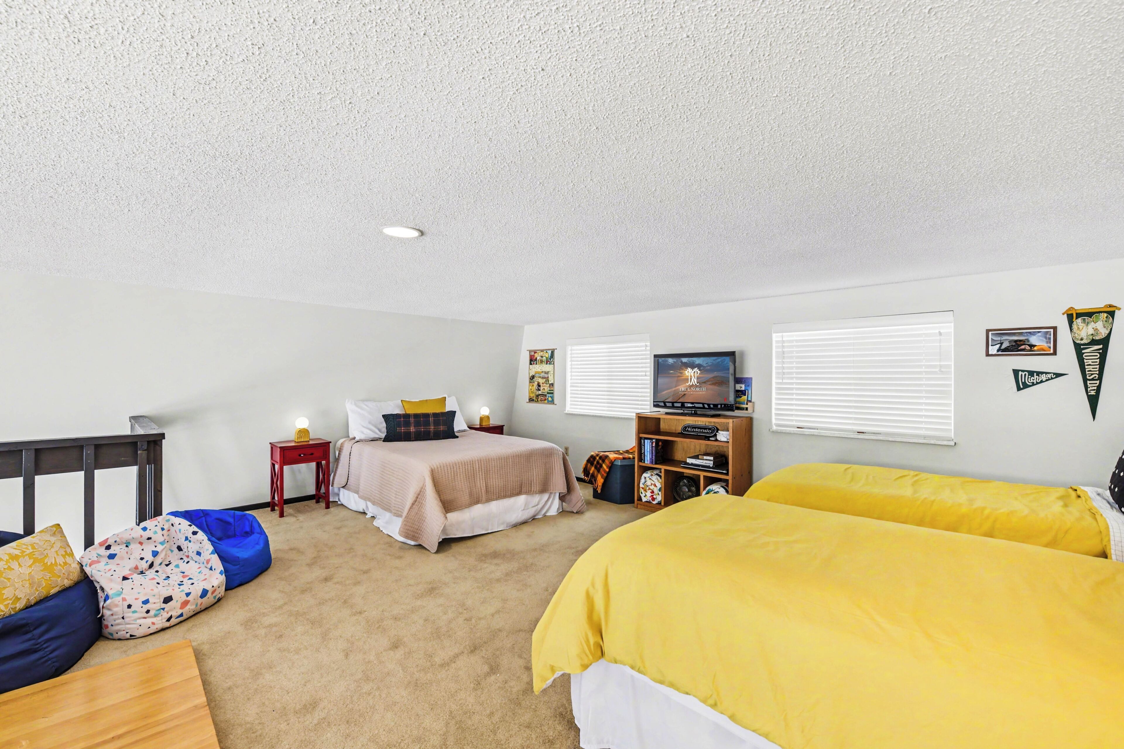 Bedroom with yellow bedding and seating area at Sugarloaf Chalet in Arcadia, Michigan