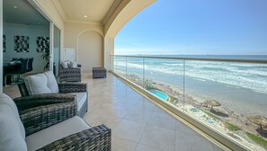 A balcony with wicker furniture, a pool, and a view of the ocean. - Modern-MarYSol Condo-BeachfrontAccess-2BR-Rosarito (Rosarito)