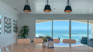 A modern kitchen with granite countertops, a large island, and a view of the ocean. - Modern-MarYSol Condo-BeachfrontAccess-2BR-Rosarito (Rosarito)
