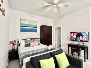 Ein Hotelzimmer mit Bett, Fernseher, Kleiderschrank und Schreibtisch.