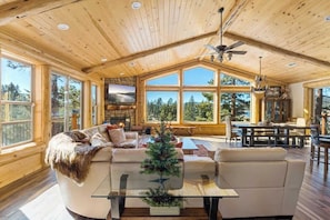 A spacious living area with a fireplace, large windows, and a dining area.
