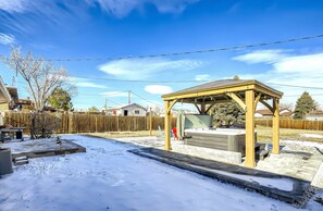 A covered outdoor area with a wooden structure, a stone bench, and a snow-covered ground.