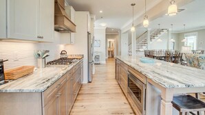 Una cocina moderna con encimeras de mármol, armarios de madera y una isla central.