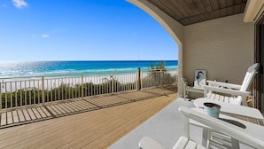 Un balcon avec vue sur l’océan, des meubles d’extérieur blancs et une petite table avec un seau.
