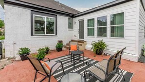 Ein Patio mit Streifenoptik-Teppich, Metallstühlen und Blumentöpfen.