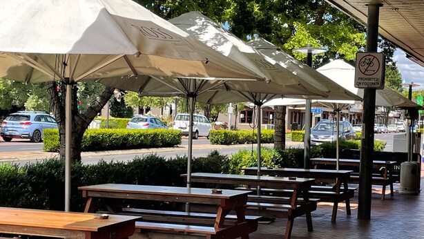 Outdoor seating with umbrellas, a paved walkway, and a no cycling sign. - Hotel Canobolas (Orange)