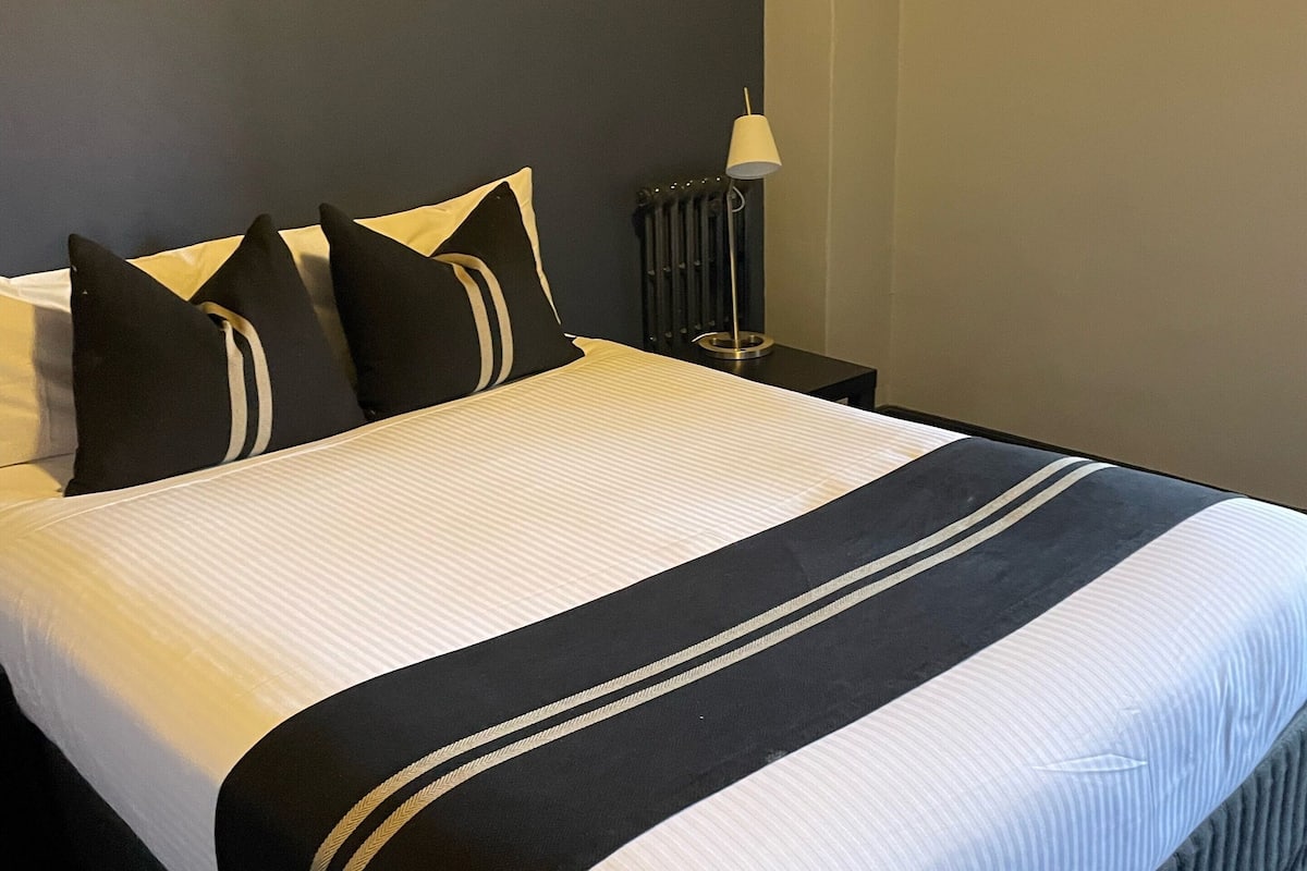 A neatly made bed with a black and white striped bedspread and two pillows.
