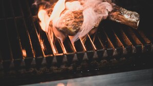 A grill with flames and smoke, indicating cooking activity. - Hotel Canobolas (Orange)