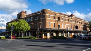 A multi-story brick building with a flat roof, large windows, and a corner entrance. - Hotel Canobolas (Orange)