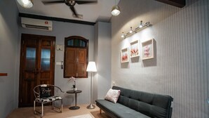 A cozy room with a green sofa, a small table with a lamp, a chair, and a decorative plant. - Le meilleur (George Town)