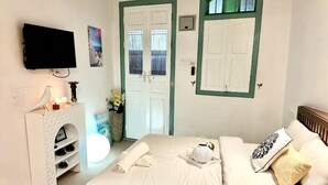 A bedroom with a bed, a TV, a fireplace, and a door with a window. - Le meilleur (George Town)