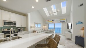 A modern kitchen with a large island, white cabinetry, and a view to the outside.