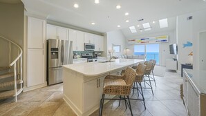 A modern kitchen with white cabinets, stainless steel appliances, and a large island with bar stools.