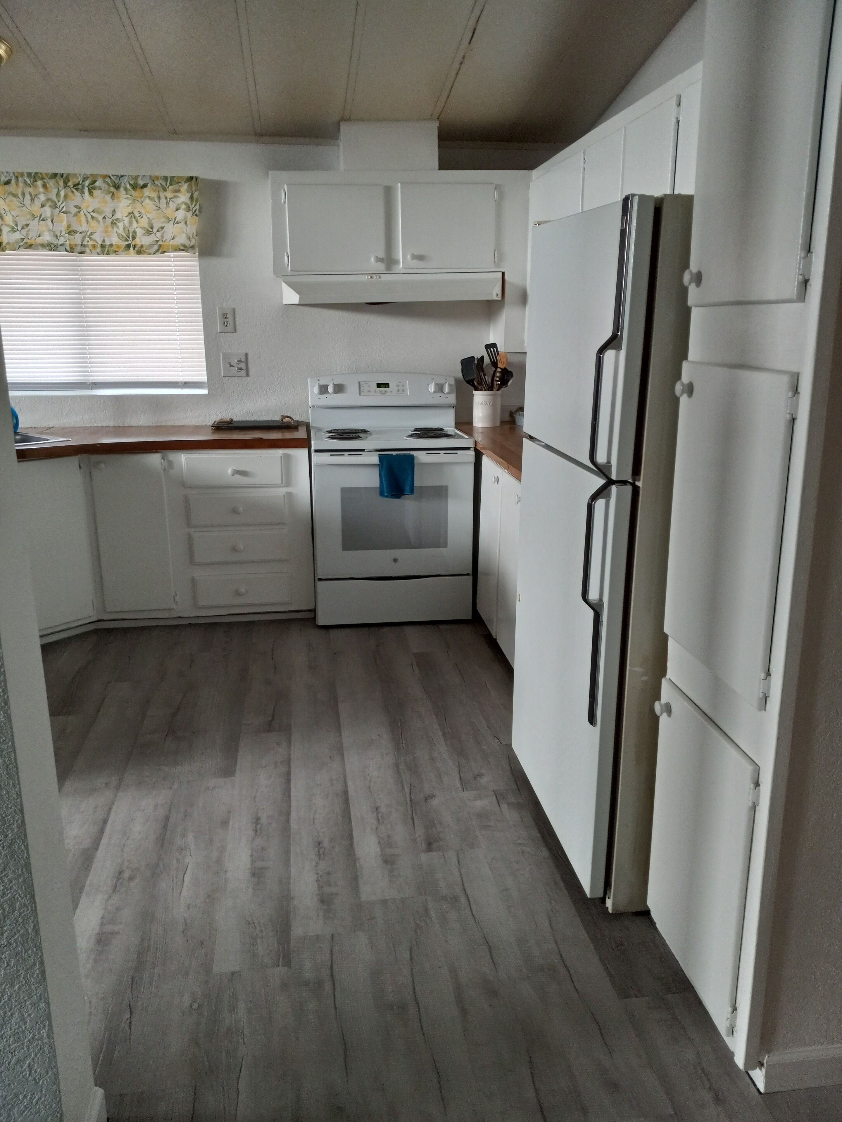 A compact kitchen with white cabinets, a white stove, and a refrigerator.