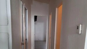 A narrow hallway with wooden flooring and white walls. - The Green River House (Bullhead City)