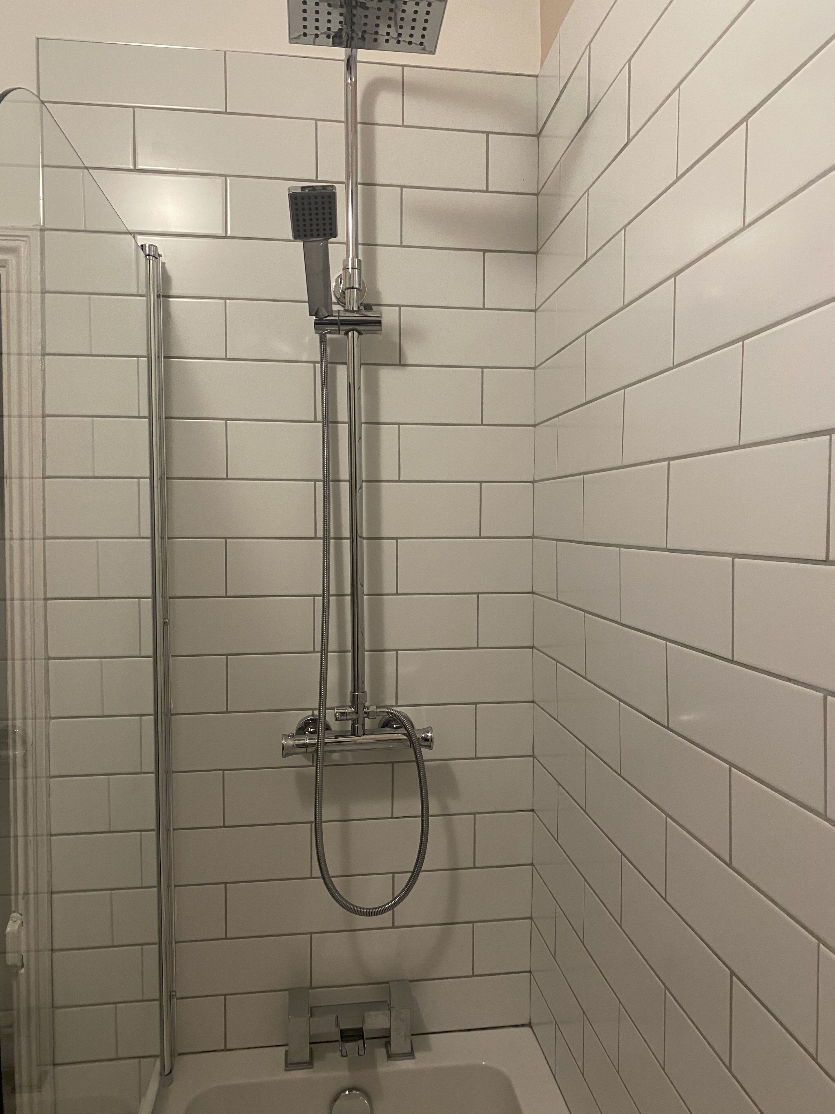 Une douche équipée d’un pommeau de douche à main, d’un flexible de douche et d’un tuyau flexible.