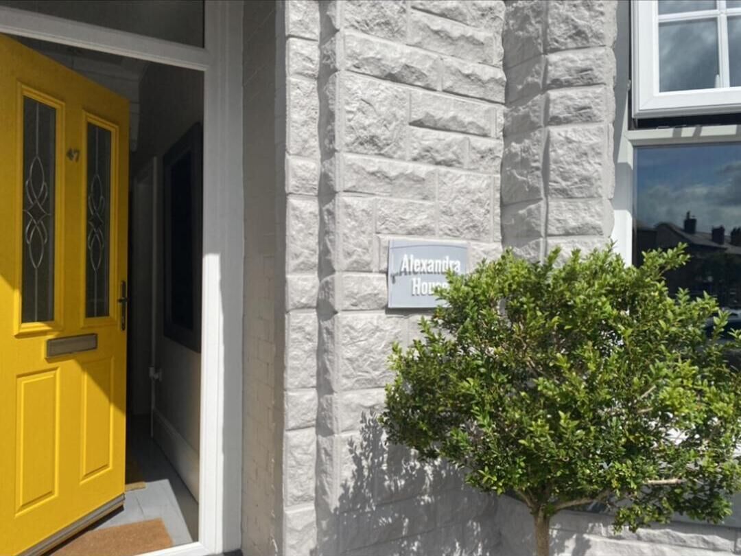 A house with a yellow door and a sign reading "Alexandra House."