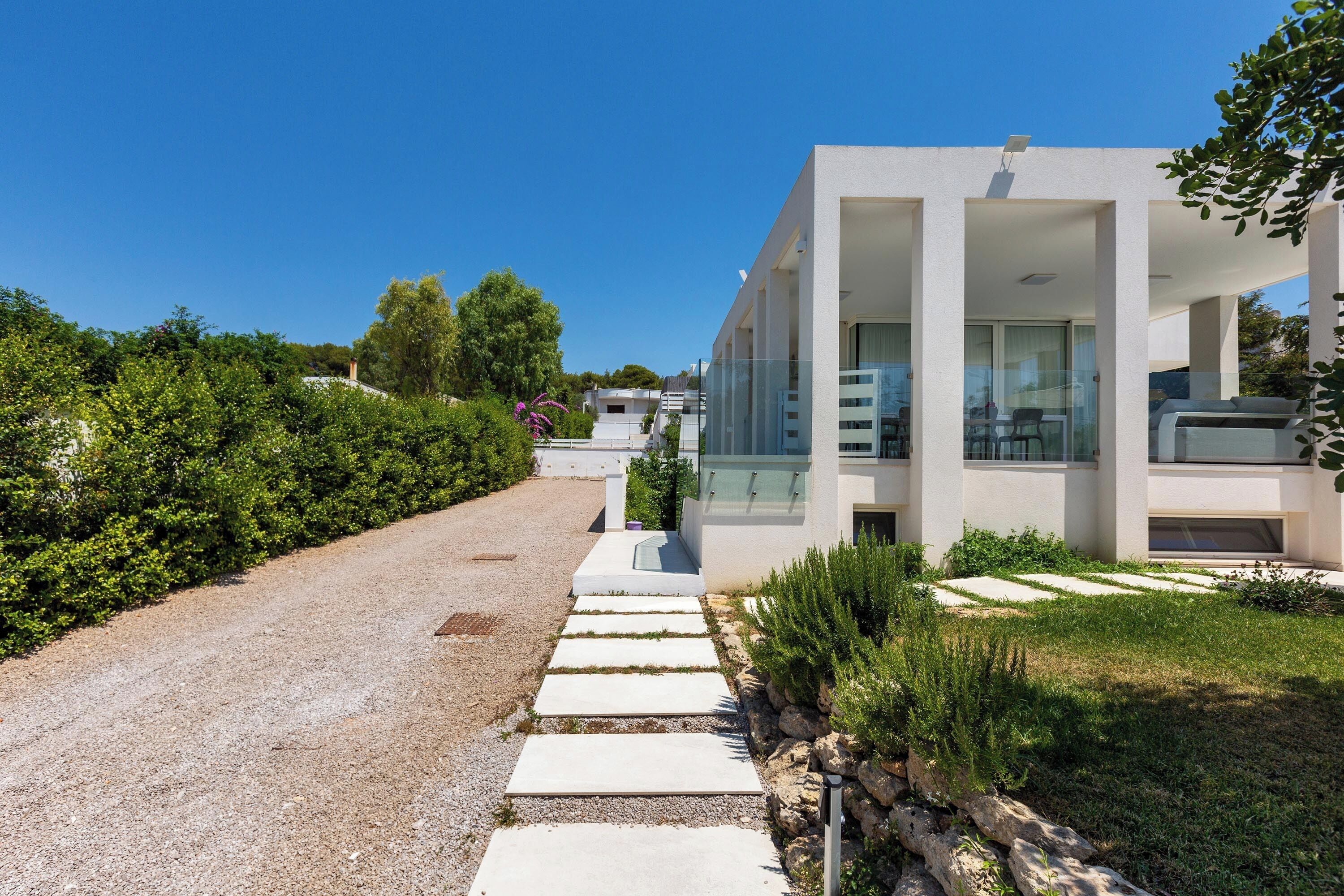 A modern building with a gravel driveway and a grassy area.