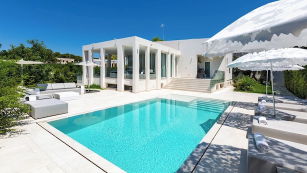 A modern poolside area with a clear pool, white outdoor furniture, and a covered seating area. - 2503 B&B Villa Eragea - Camere Superior by Barbarhouse (Matino)