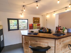 A bar area with a wooden counter, bar stools, hanging lights, a window, and various snacks and beverages on the wall. - Rockville (Greencastle)
