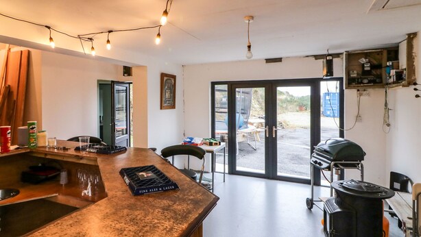 Et køkken med barområde, grill og en skydedør til et udendørs område.