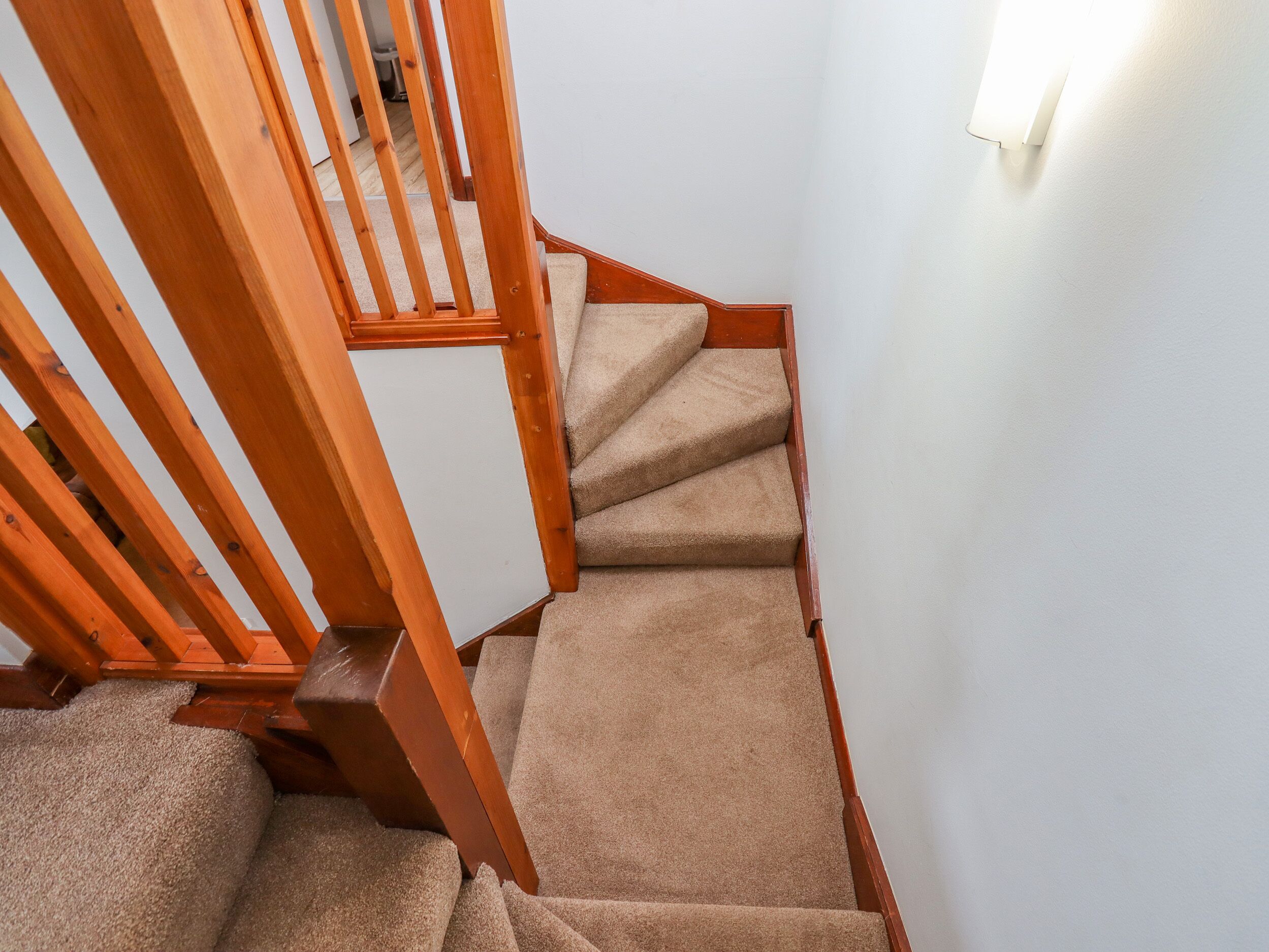 A wooden staircase with carpeted steps leading to a landing.