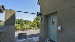 Un bâtiment avec une porte verte, un banc et une rambarde en métal.