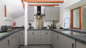 Une cuisine moderne avec des meubles gris, une hotte en acier inoxydable et un four encastré.