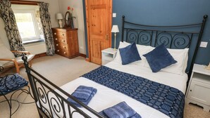 A bedroom with a bed, a dresser, a chair, and a window with curtains. - 2 Yr Hen Felin (Haverfordwest)
