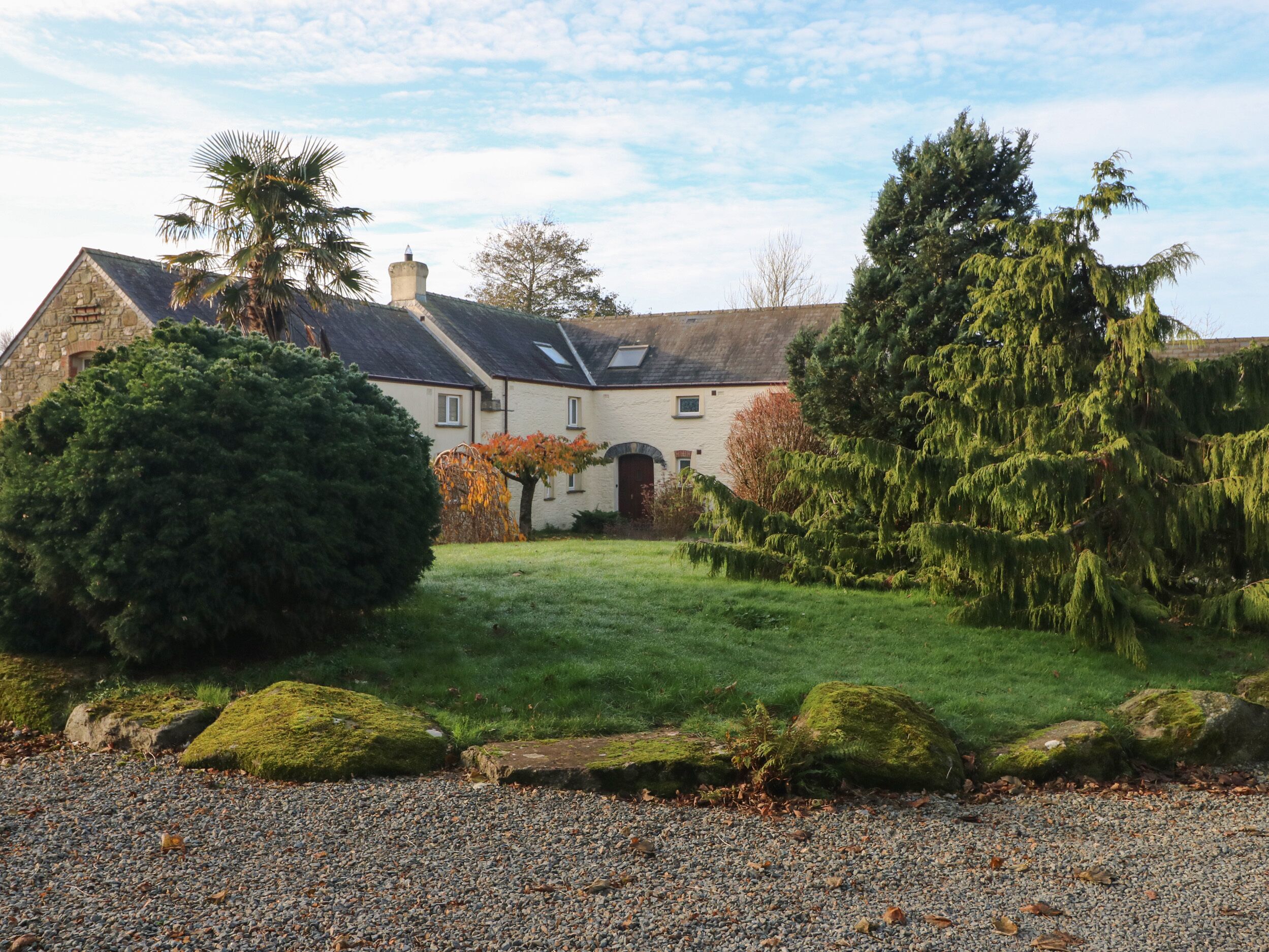 A stone house with a well-maintained lawn and large trees.