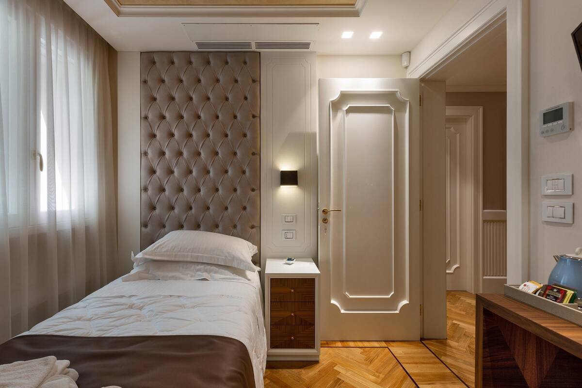 A neatly arranged bedroom with a bed, bedside table, and a door leading to another room.