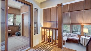 A room with a wooden floor, a bench, a table with a lamp, and a bed with a floral bedspread. - Walk to the Lake Amazing 5 Bedrm - VH#343 by Bear Valley Vacation Rentals (Arnold)