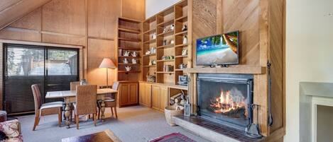 Un salon chaleureux avec une cheminée, des étagères en bois et un téléviseur.