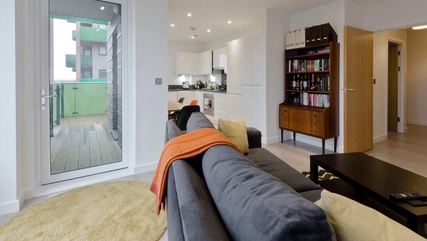 A modern living room with a sofa, a coffee table, and a bookshelf. - 2-bed Apartment Only 15 Mins From Central London (Wembley)