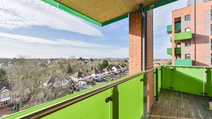 A balcony with a green railing overlooking a residential area with houses and trees. - 2-bed Apartment Only 15 Mins From Central London (Wembley)