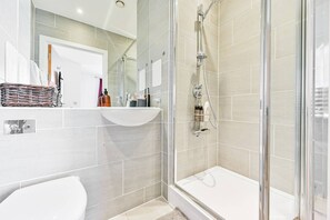 Une salle de bain moderne avec une douche en verre, un lavabo blanc et un miroir au-dessus du lavabo.