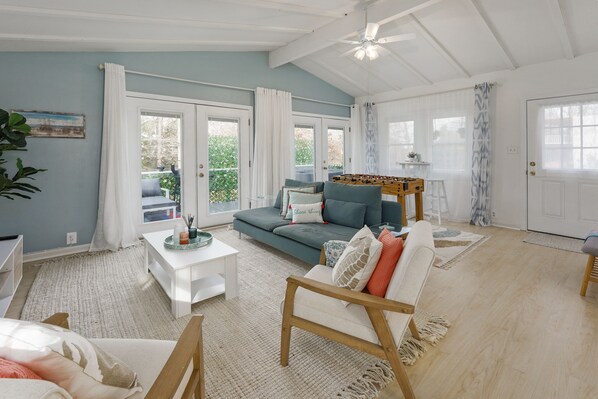 A spacious living room with a sofa, coffee table, and a foosball table.