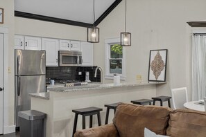 A modern kitchen with stainless steel appliances, a granite countertop, and a bar area with stools.