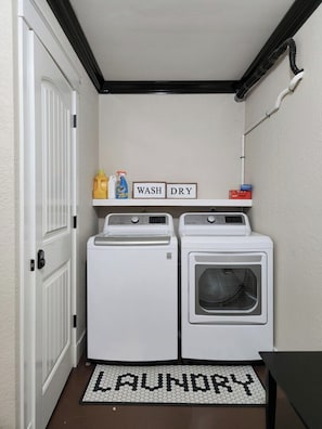A laundry room with two white washing machines, a shelf with detergent bottles, and a 'WASH DRY' sign. - Deja Too - Three Bedroom House, Sleeps 10 (Osage Beach)