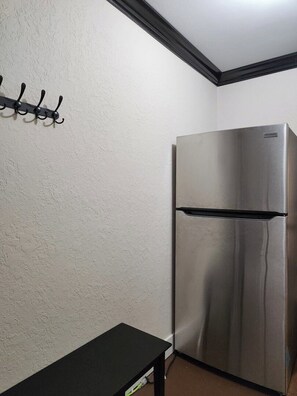 A kitchen with a stainless steel refrigerator, a black countertop, and a wall-mounted hook.