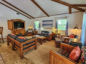 Un salon chaleureux avec des meubles en bois, un téléviseur et un tableau représentant une scène de plage.