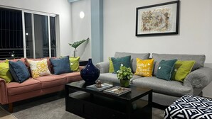 A living room with a pink sofa, grey sofa, and a coffee table with books and a vase.