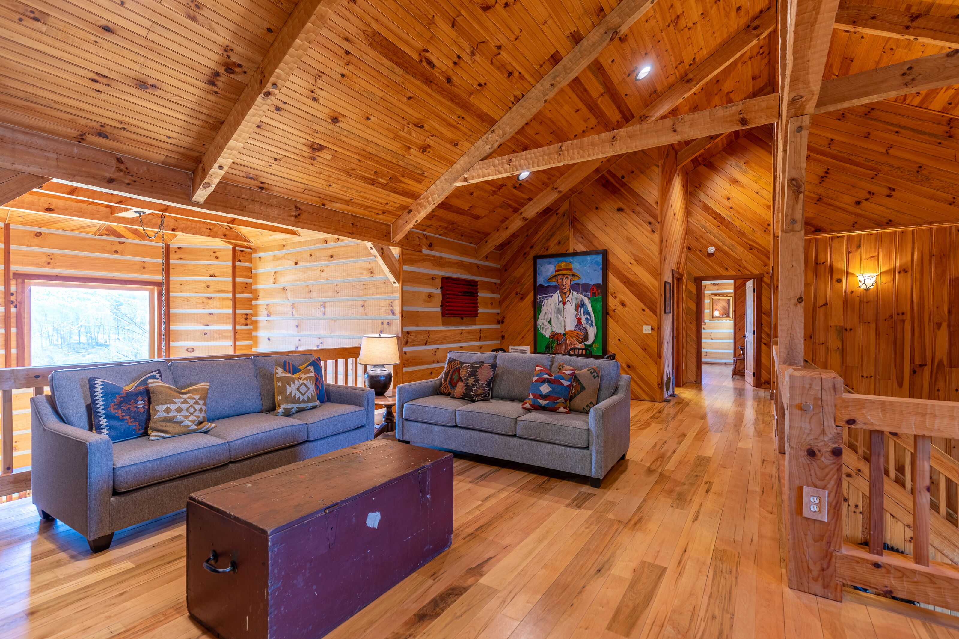A log cabin interior with two sofas, a wooden bench, and a painting on the wall.