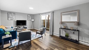 Un salon moderne avec un canapé, un fauteuil, une télévision et une console.