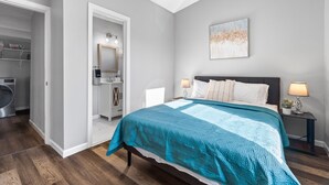 Une chambre à coucher avec un lit, des tables de chevet, une commode, un miroir et un tableau au mur.