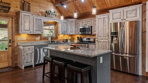 Une cuisine moderne dotée de plans de travail en granit, d’appareils électroménagers en acier inoxydable et de meubles en bois.